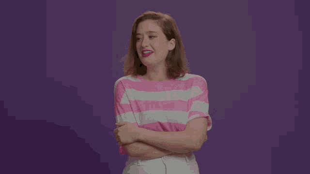 a woman wearing a pink and white striped shirt with her arms crossed