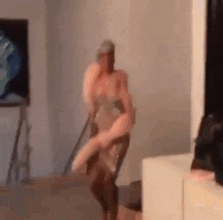 a man is holding a woman in his arms and dancing in a living room .