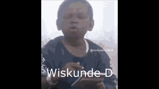 a young boy is holding a cell phone and making a funny face while sitting at a table .