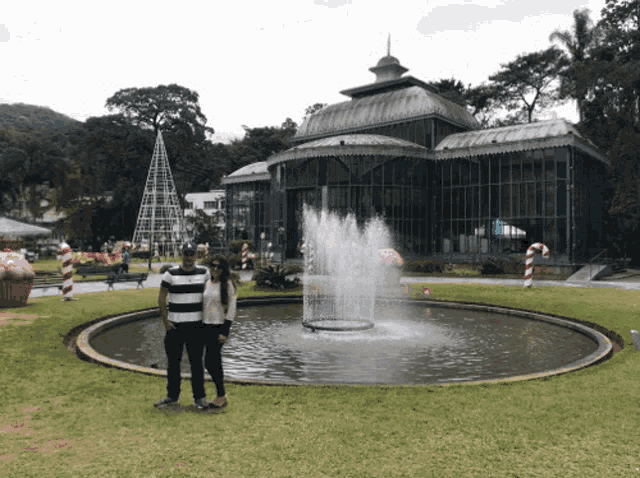 a man and a woman are standing in front of a fountain