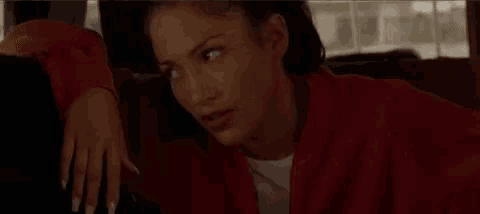 a woman in a red jacket is sitting in the back seat of a car with her hand on the back seat .