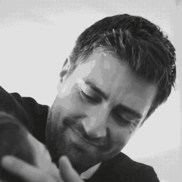 a man with a beard is smiling and looking down