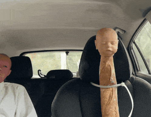 a mannequin head with a bread sticking out of it is in the back seat of a car