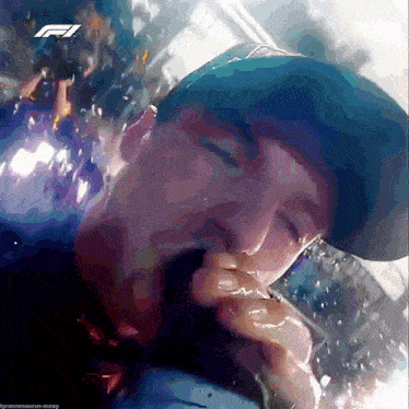 a man in a blue hat is drinking from a bottle with a f1 logo in the background