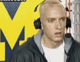 a man wearing headphones stands in front of a large m