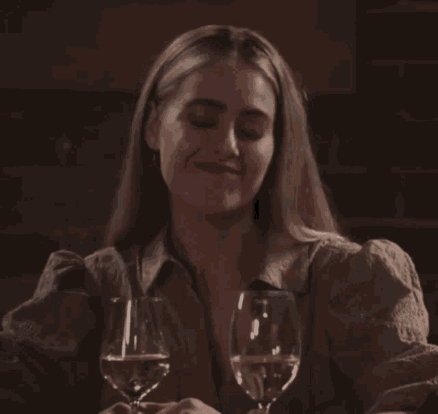 a woman sitting at a table with two glasses of wine in front of her