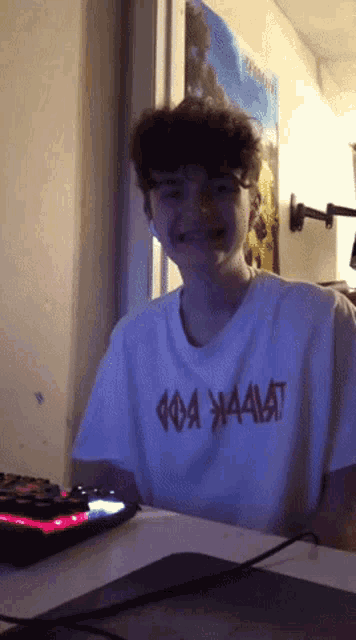 a young man wearing a white t-shirt that says ' aaaat ' on it