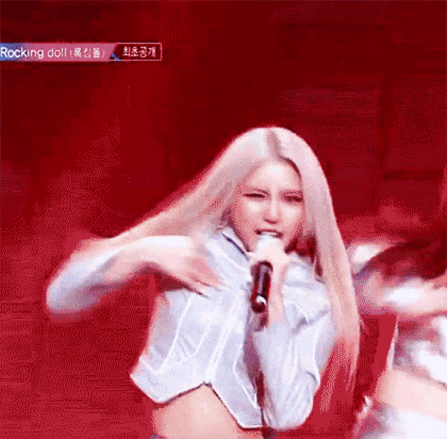 a woman with long blonde hair is singing into a microphone on stage .