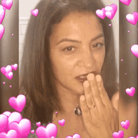 a woman is blowing a kiss with her hand in front of her face .