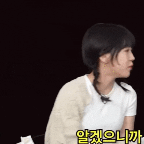 a woman wearing a white shirt and a beige sweater with korean writing on it
