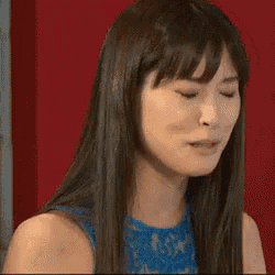 a woman with long black hair is smiling with her eyes closed .