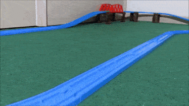 a toy train is on a track with a bridge in the background
