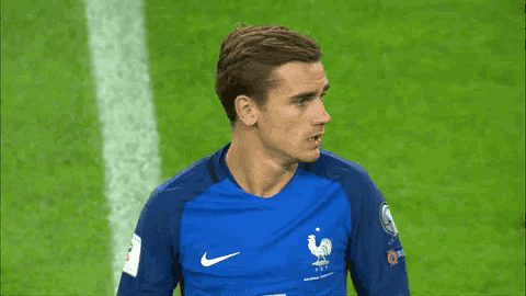 a soccer player wearing a blue shirt with a rooster on the front
