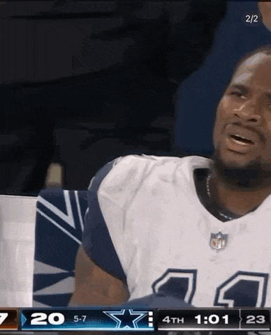 a man in a cowboys jersey is sitting in the stands during a game .
