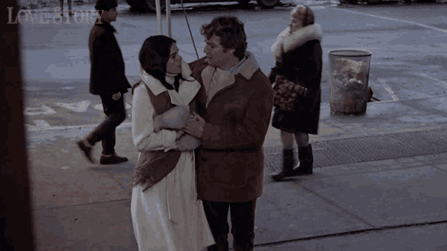 a man and a woman are hugging on a sidewalk with the words lovestory written above them