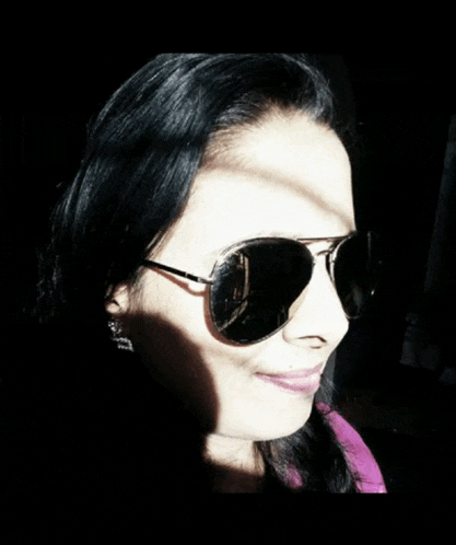 a woman wearing a pair of aviator sunglasses is smiling