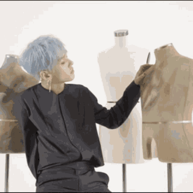 a man with blue hair is holding a mannequin