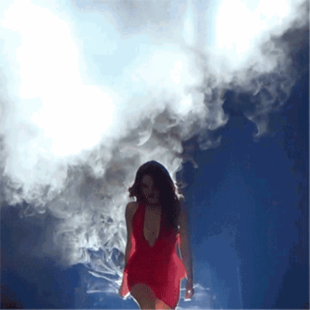 a woman in a red dress stands in a cloud of smoke