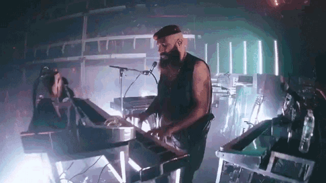 a man with a beard is playing a keyboard in front of a crowd