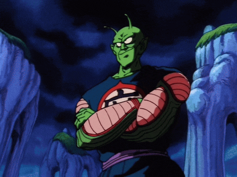 piccolo from dragon ball z stands with his arms crossed in front of a cliff