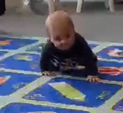 a baby is crawling on a blue and green rug .