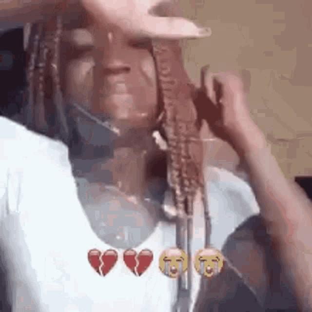 a woman with dreadlocks is crying while holding a broken heart .