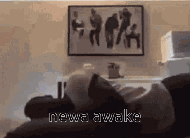 a person is laying on a couch in a room with a picture on the wall that says ` ` newa awake ` `