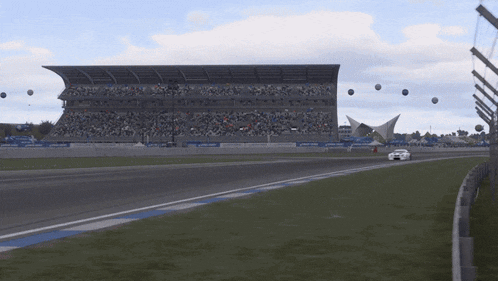 a race car is driving down a track in front of a stadium
