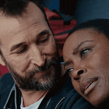 a man and a woman are looking at each other and the woman is smiling