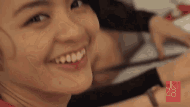 a close up of a woman 's face smiling and looking at the camera
