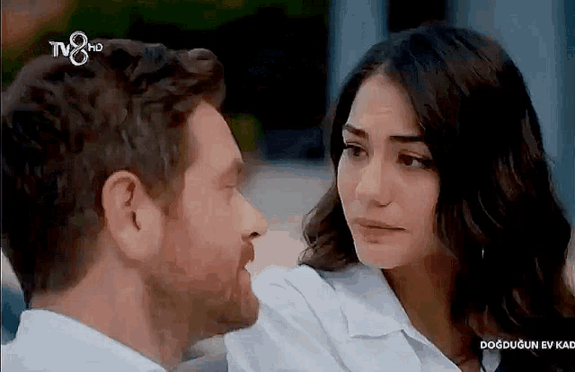 a man and a woman are looking into each other 's eyes while sitting next to each other .