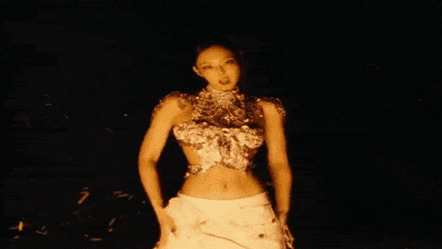 a close up of a woman 's face in a dark room with fire in the background .