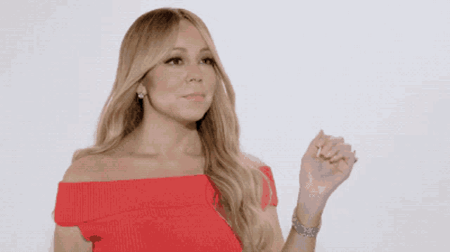 a woman in a red off the shoulder top is holding her hand up