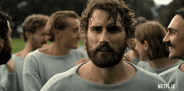 a man with a beard is standing in a crowd with netflix written on the bottom of the screen