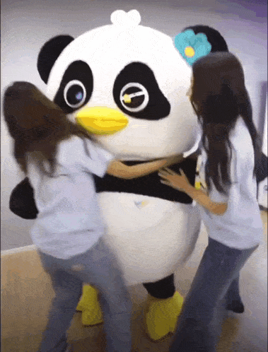 three girls hugging a panda mascot with a yellow beak