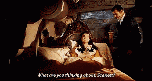 a man standing next to a woman in a bed asking her what she is thinking about