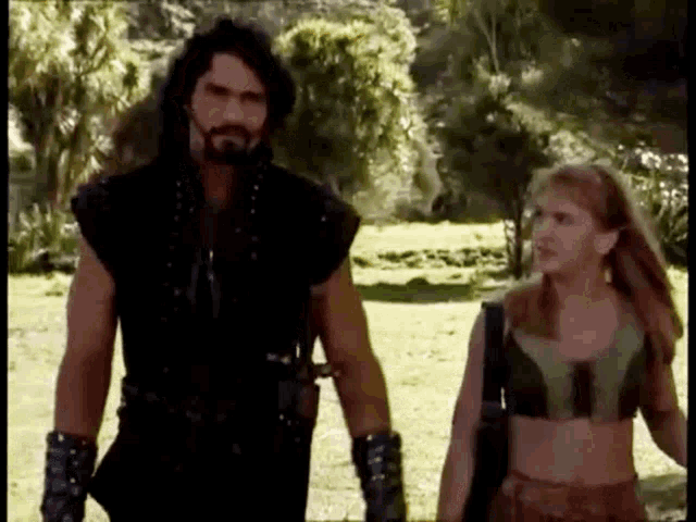 a man and a woman are standing next to each other in a grassy field .