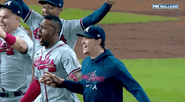 a group of baseball players are celebrating on a field with fox world series in the background
