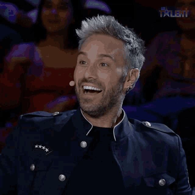 a man is laughing in front of a sign that says the talent
