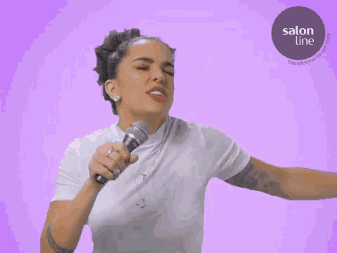 a woman is singing into a microphone with a salon line logo in the background
