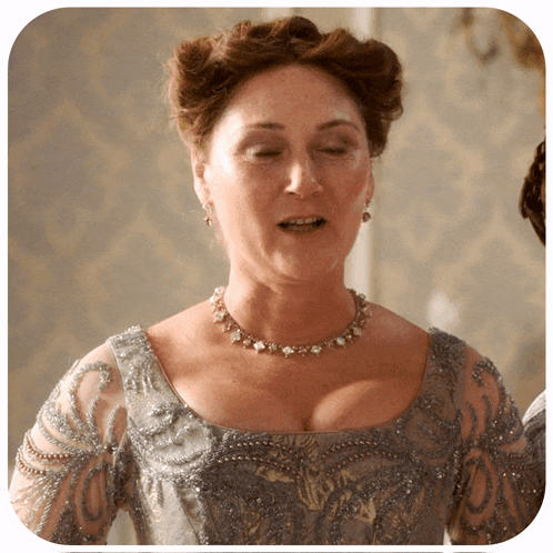 a woman is wearing a necklace and earrings and a gray dress