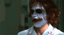 a woman with a white face painted like the joker from the movie the dark knight rises .