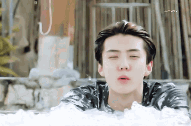 a young man is laying in a pool of water with the word monx on the bottom right