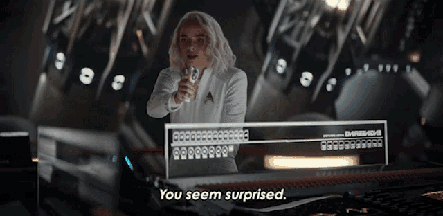 a woman in a white shirt is holding a gun and says you seem surprised