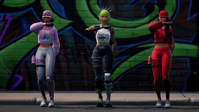 three girls are standing in front of a graffiti wall and one has a shirt that says paintball