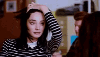 a woman in a striped shirt is holding her head .