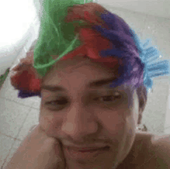 a man with a clown wig on his head looks at the camera