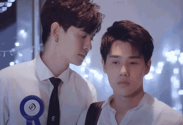 two men are standing next to each other and one has a blue ribbon on his shirt that says ' a ' on it