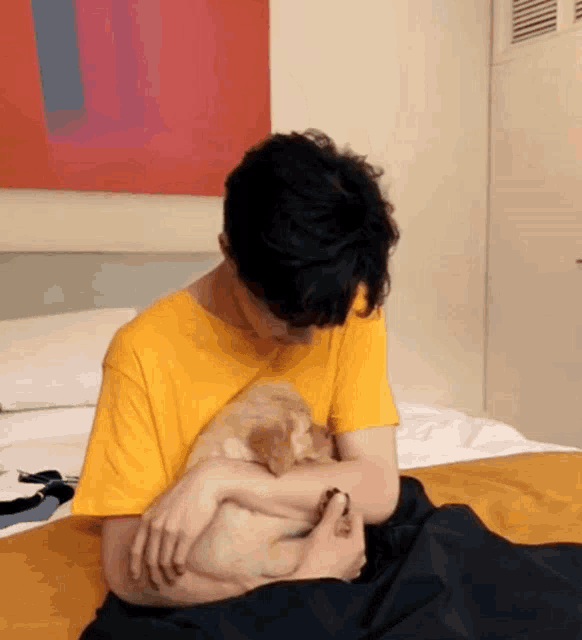 a man in a yellow shirt is holding a puppy in his lap