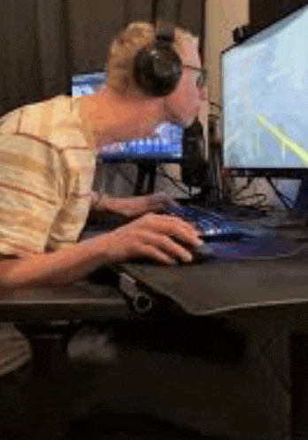 a man wearing headphones is sitting at a desk in front of a computer .